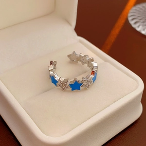 Detail of silver star ring with blue enamel and small diamonds in a white jewelry box