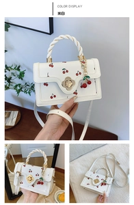Detail of off-white crossbody bag with red cherry print and golden petal swivel lock
