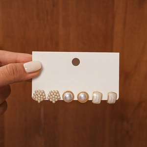 Macro detail of a 6-piece earring set with pearls and enamel on a white display card