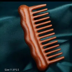 Handcrafted sandalwood massage hair comb with ergonomic handle on green silk background