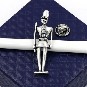 Close-up of silver Nutcracker soldier brooch with rhinestones on blue textured gift box