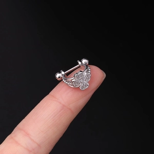 Detailed macro view of a silver clover stud earring with tiny zircons held on a fingertip