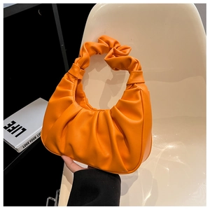 Detail of orange cloud bag featuring a soft pleated handle and smooth PU leather texture