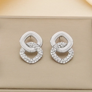 Macro shot of silver interlocking square earrings with pave cubic zirconia on beige jewelry box