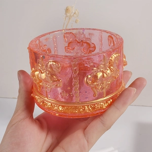 Hand holding a translucent pink striped carousel storage jar mold with gold relief