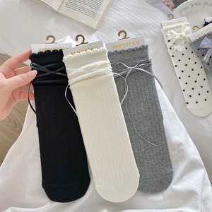Detail of sweet cotton socks with ruffled edges and delicate ribbon bows in soft knit