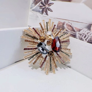 Luxury sunflower brooch in gold alloy with red and grey vintage crystals on white background