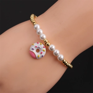 Detail of beaded bracelet with gold copper beads, white pearls and a colorful donut charm