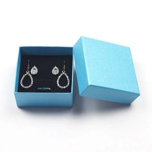 Detailed set of teardrop rhinestone earrings and blue gem ring in a textured gift box