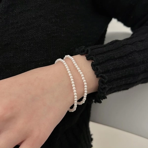 Detail of double-layer S925 sterling silver pearl bracelet on wrist with black knit sleeve