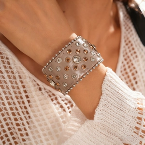 Détail d'un bracelet en cuir bohème avec strass champagne et bordure de perles argentées