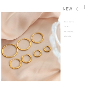 Detailed set of seven polished gold titanium hoop earrings in various sizes on satin