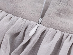 Macro view of invisible zipper and pleated mesh fabric detail on grey elegant top