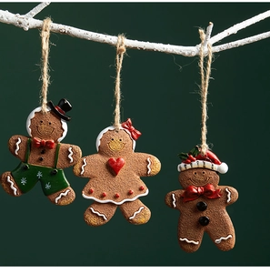 Detailed view of three resin gingerbread man charms hanging on branches for Christmas
