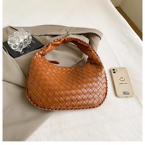 Detailed close-up of a brown woven leather hobo bag styled with fashion props