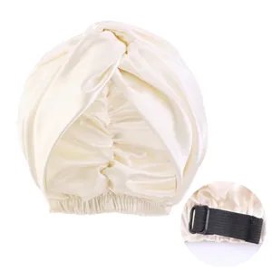 Detail of adjustable elastic strap and buckle on cream faux silk twisted sleeping bonnet