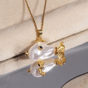 Detail of fish pendant with pearl body and blue gemstone eye on a gold chain