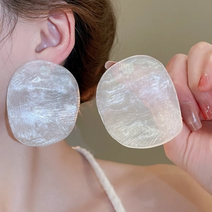 Macro shot of irregular resin earrings with ice-crack texture and pearlescent white finish
