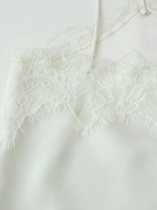 Détail de la robe en satin blanc avec dentelle de cils délicate et fines bretelles