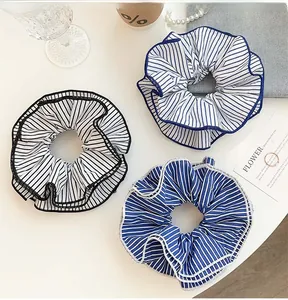 Flat lay of three striped fabric scrunchies with ruffle edges on a minimalist background