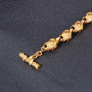 Détail macro du bracelet à maillons crâne doré avec fermoir à bascule sur fond noir