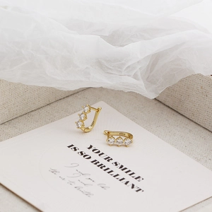 Detail of S925 sterling silver stamp and sparkling zircons on gold U-shaped earrings