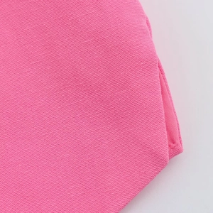 Gros plan sur la texture du coton rose et les coutures précises de l'ensemble gilet