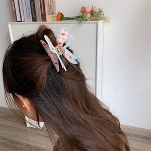 Detail of butterfly hair claw with pink checkered cherry print on a half-up hairstyle