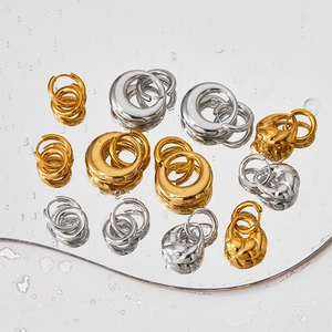 PVD gold and silver detachable double hoop earrings displayed on a reflective water surface