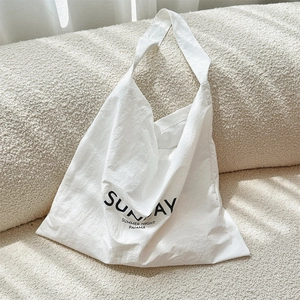 Detail of white canvas tote bag with black Sunday print on textured fabric surface
