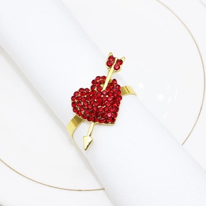 Macro shot of gold heart arrow napkin ring with red rhinestones on white linen
