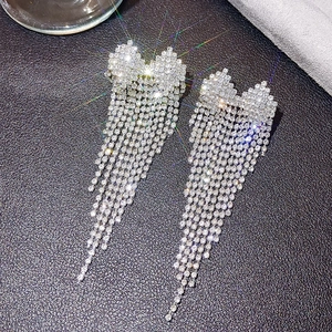 Detailed view of silver long tassel earrings with sparkling rhinestones and heart studs