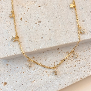 Gold stainless steel necklace with sparkling zircon star charms on stone background