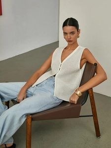 Close-up of white hollow-out knit vest with thick textured stitch and V-neckline detail