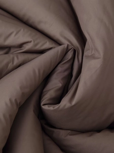 Detail of dark brown puffer jacket fabric showing smooth texture and soft pleats