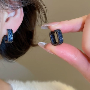 Detail of a rectangle hoop earring featuring blue micro-pave zircons on dark metal base