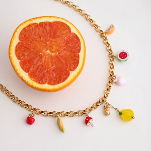 Detail of 18K gold chain necklace with colorful fruit charms and real orange slice