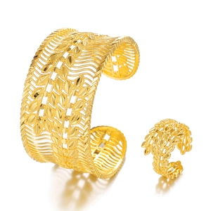 Close-up of golden hollow leaf patterns on the adjustable bangle and ring set