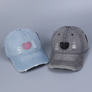 Detailed view of heart-shaped CUUD embroidery on distressed washed denim baseball caps