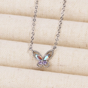 Macro shot of silver butterfly necklace with iridescent opal stones and purple gems