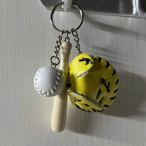Detailed close-up of a mini baseball keychain set with ball bat and yellow glove