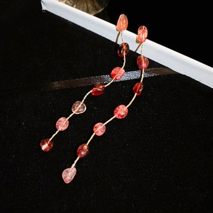 Close-up of strawberry crystal tassel earrings with gold chains on black velvet box