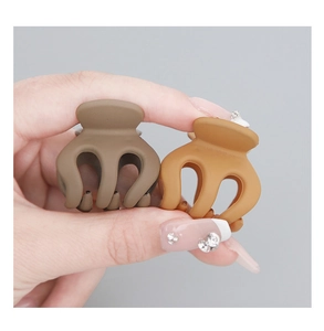 Detail shot of matte mini pumpkin claw clips in brown and yellow colors for hair