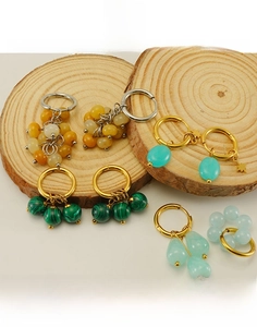 Detail of 18k gold plated titanium earrings and rings with natural malachite on wooden trays
