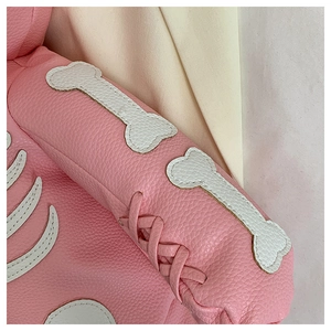 Detailed close-up of pink leather pet clothing featuring a white bone patch and woven ties