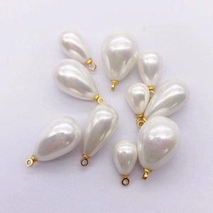 Macro view of teardrop faux pearl pendants with gold metal loops for DIY jewelry making