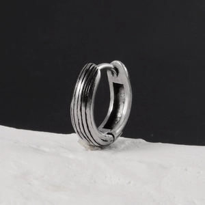 Vue macro d'une boucle d'oreille charnière en acier argenté à motifs rayés