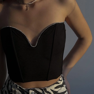 Detailed view of black V-neck corset top with sparkling rhinestone trim and smooth fabric