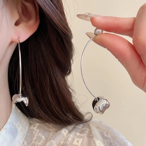Close-up of silver curved earrings with irregular metal charms and round white pearls