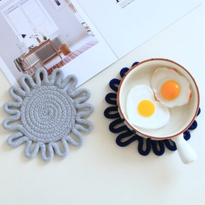Close-up of hand-woven cotton sunflower coasters in grey and navy blue for table protection